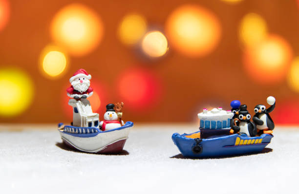 Santa and Snow man on one boat with three penguins on the other boat stock photo