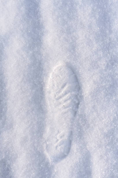 istock Human foot print in shoes on white freshly fallen snow. 1054904174
