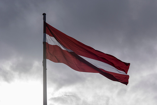 Flag of Latvia against dramatic Sky