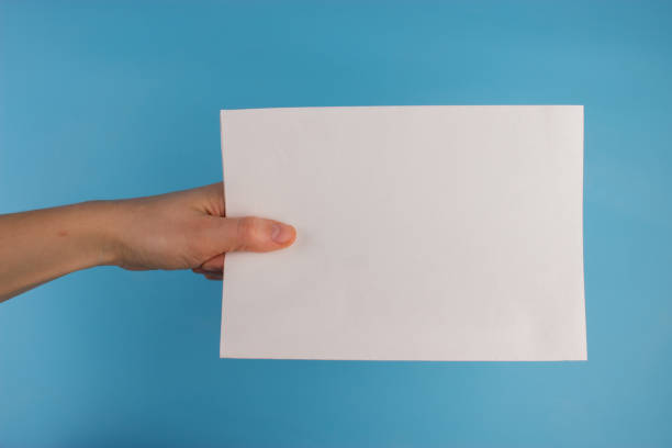 istock Blank paper in hand not isolated on blue background 1054908282