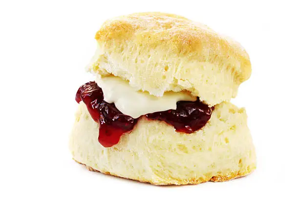 Photo of Close-up of a scone with jelly and butter isolated on white