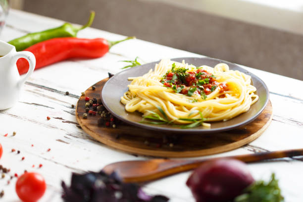 istock Plate with pasta with sauce Cherry, chilli, tomato, basil, spices, tarragon, onion. Ingredients for cooking pasta. 1054913360