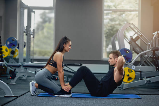 istock Man doing abdominal crunches press exercise with female personal trainer. 1054915812
