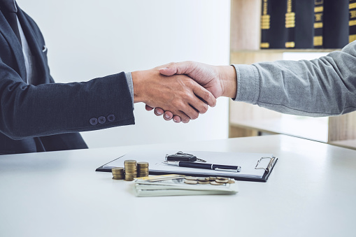 Handshake of cooperation customer and salesman after agreement, successful car loan contract buying or selling new vehicle.