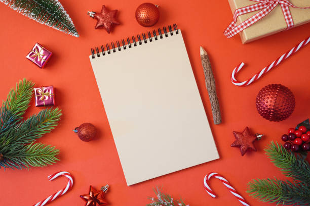 istock Christmas holiday background with notebook and decorations on red table 1054918904