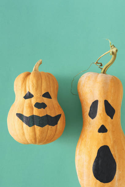 istock Flat lay two funny scary face Halloween pumpkins Fall autumn halloween minimal top view 1054919228