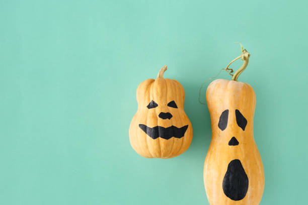 istock Flat lay two funny scary face Halloween pumpkins Fall autumn halloween minimal top view 1054919294