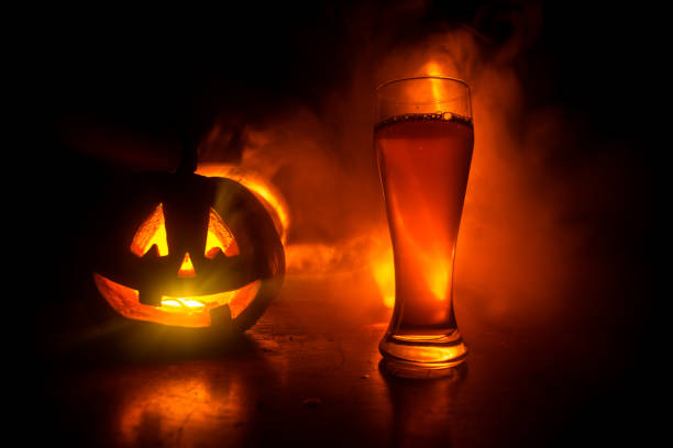 ハロウィーンのため木材の背景にカボチャの冷たい光のビールのグラス。新鮮なビールと暗いトーンの霧の背景にカボチャのガラス - glass autumn halloween food ストックフォトと画像