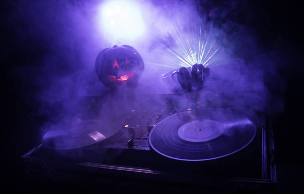 istock Halloween pumpkin on a dj table with headphones on dark background with copy space. Happy Halloween festival decorations and music concept 1054920438