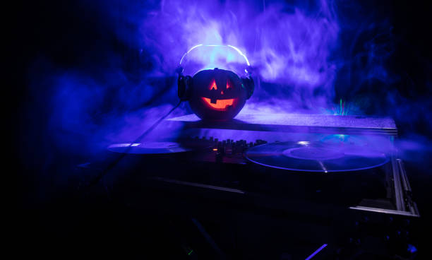istock Halloween pumpkin on a dj table with headphones on dark background with copy space. Happy Halloween festival decorations and music concept 1054920440