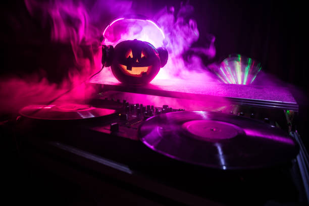 istock Halloween pumpkin on a dj table with headphones on dark background with copy space. Happy Halloween festival decorations and music concept 1054920444