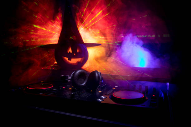 istock Halloween pumpkin on a dj table with headphones on dark background with copy space. Happy Halloween festival decorations and music concept 1054920456