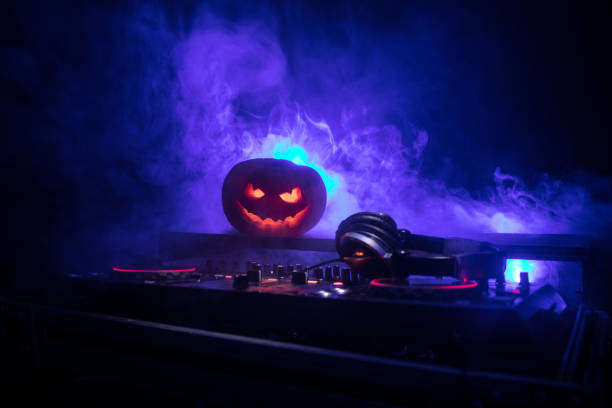 istock Halloween pumpkin on a dj table with headphones on dark background with copy space. Happy Halloween festival decorations and music concept 1054920464