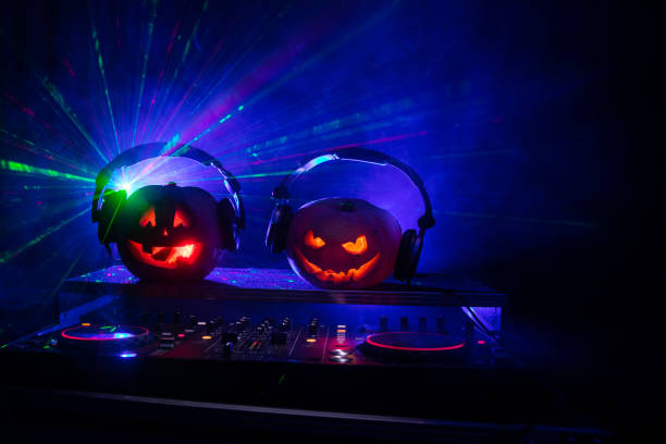 istock Halloween pumpkin on a dj table with headphones on dark background with copy space. Happy Halloween festival decorations and music concept 1054920472