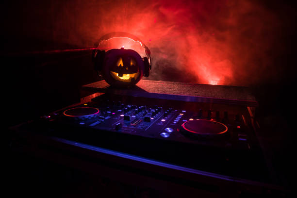 istock Halloween pumpkin on a dj table with headphones on dark background with copy space. Happy Halloween festival decorations and music concept 1054920478