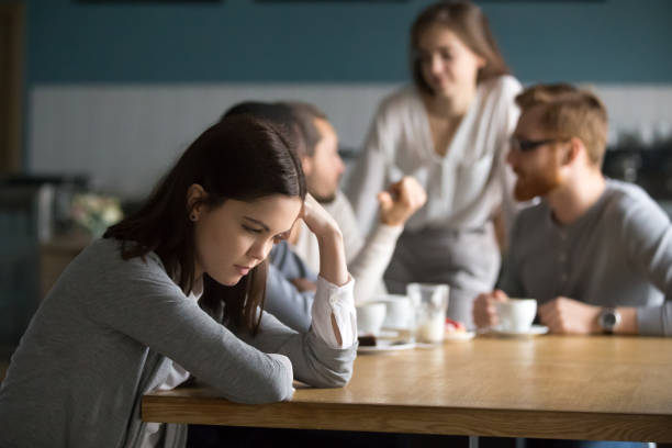 Sad young girl feeling lonely sit alone in coffee shop Upset young girl sit alone at coffee table in café feeling lonely or offended, sad female loner avoid talking to people, student outsider suffer from discrimination, lacking friends or company exclusive stock pictures, royalty-free photos & images