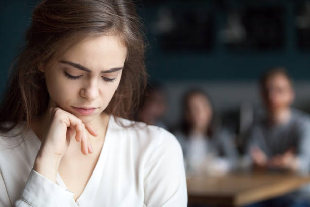 Sad young girl feeling lonely sitting alone in cafe Upset young girl sitting alone in cafÃ© offended at friends joke, sad millennial woman suffer from low self-esteem, depressed female outcast feeling outsider hanging out with company in coffeeshop admiration photos stock pictures, royalty-free photos & images