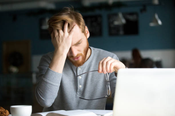 istock Tired male annoyed with difficult studying sitting in cafe 1054920630