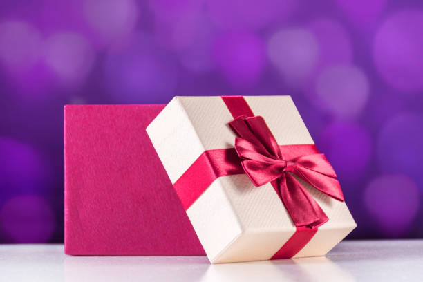 istock Red open gift box with bow on white desk and purple bokeh 1054922204