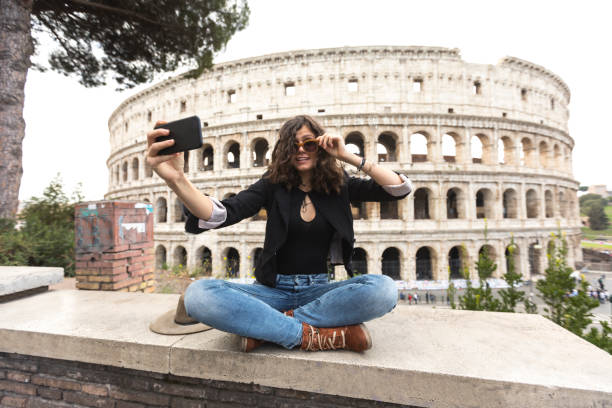 femme souriante avec lunettes de soleil en dehors de selfie - international landmark italy amphitheater ancient photos et images de collection