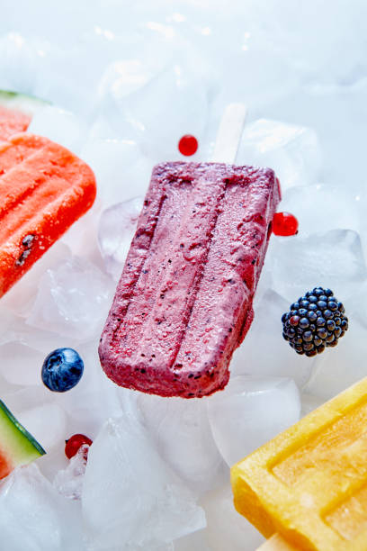 istock Frozen different fruit juices on a stick on ice cubes with different berries. Sweet healthy dessert. Top view 1054923062