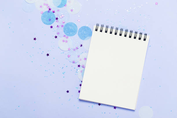 istock Empty note pad on blue frozen festive background with confetti and sparkles. 1054927286