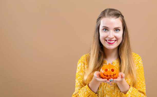 istock Young woman with a halloween pumpkin 1054927564