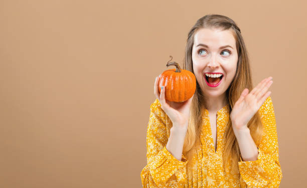 istock Young woman holding a pumpkin 1054927566