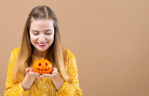 istock Young woman with a halloween pumpkin 1054927568