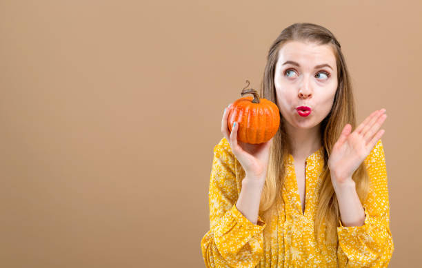 istock Young woman holding a pumpkin 1054927580