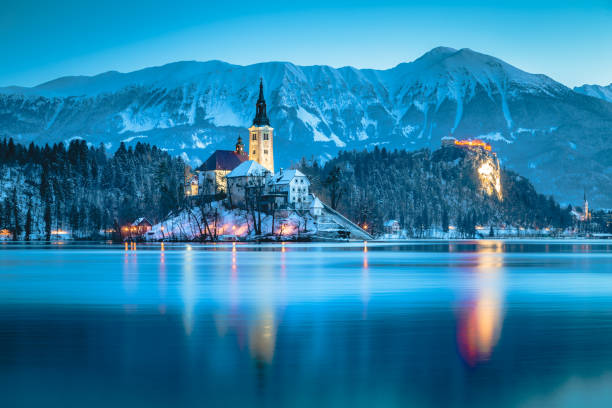 vue de crépuscule du lac de bled avec île de bled et le château de bled en hiver, slovénie - castle slovenia winter snow photos et images de collection