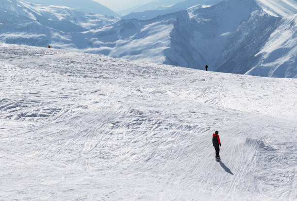 istock Snowboarder and skiers downhill on snowy slope 1054930334