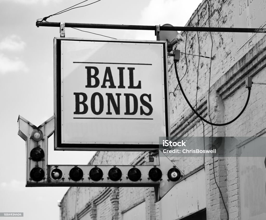 Aging Vintage Sign in Front of Samll Town Bail Bonds Office A rusty white bail bonds sign needs bulbs replaced but still points at the office entrance Bail Stock Photo