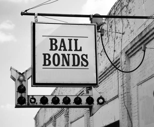 Aging Vintage Sign in Front of Samll Town Bail Bonds Office A rusty white bail bonds sign needs bulbs replaced but still points at the office entrance bail stock pictures, royalty-free photos & images