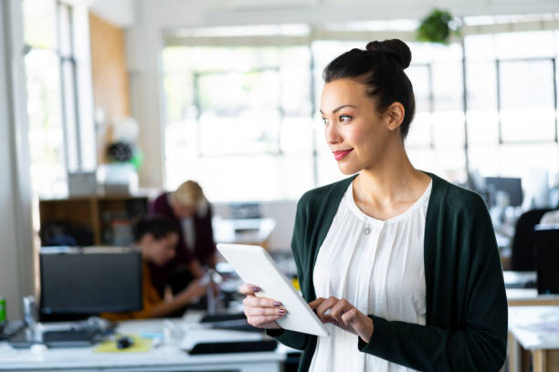 istock Businesswoman day dreaming while holding tablet 1054944674