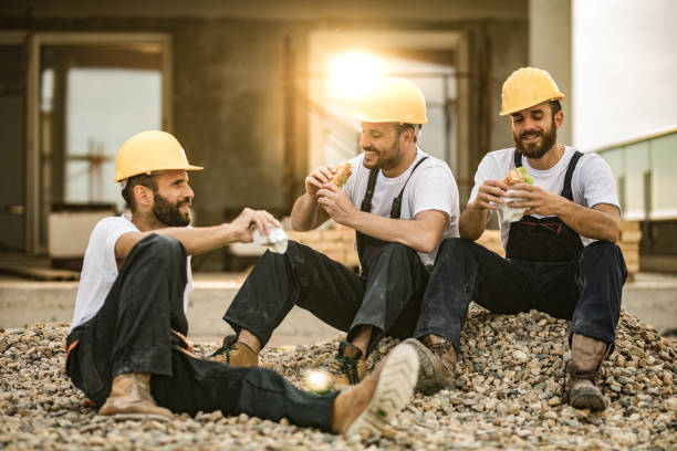 Happy manual workers eating sandwiches on a lunch break at a terrace.