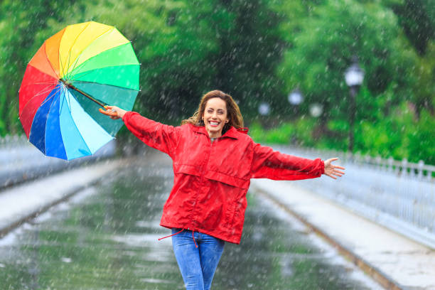 istock Woman with umbrella having fun in rainy day 1054949594