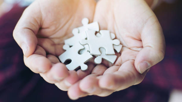 istock close up hand people putting a jigsaw puzzle on hand , business  Strategy solution concept 1054955400