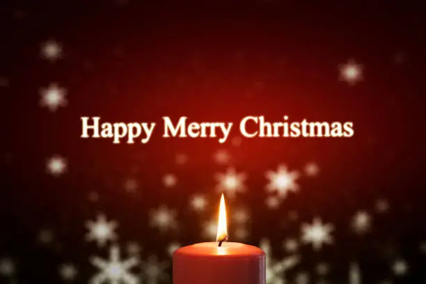 Image of burning candle and text of Happy Merry Christmas with blurred snowfall in the background