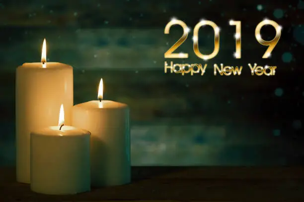 Image of Christmas candle glowing on the table with snowfall and text of 2019 Happy New Year
