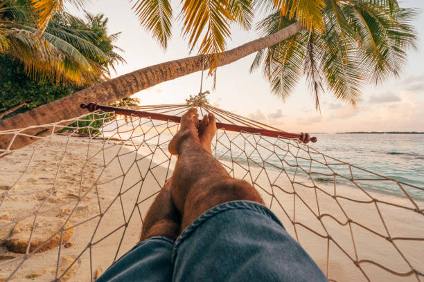 istock Man lying down on a Hammock in a paradisiac beach at Maldives 1054955952