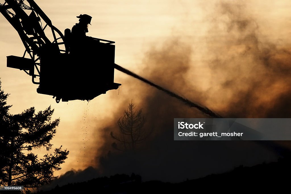 silhouette of firefighter spraying water on fire in bucket  Firefighter Stock Photo