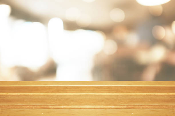 istock Empty wooden table and blurred modern warm cafe background, restaurants. Ready for product montage, bokeh , light 1054956376