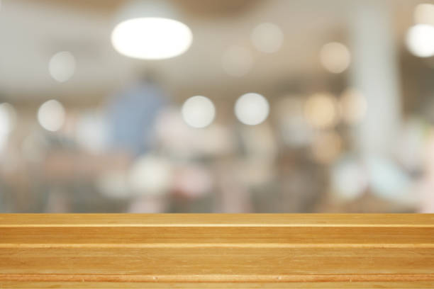 istock Empty wooden table and blurred modern warm cafe background, restaurants. Ready for product montage, bokeh , light 1054956384