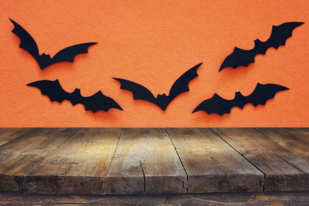 istock Halloween holiday concept. Empty rustic table in front of black bats background. Ready for product display montage. 1054956492