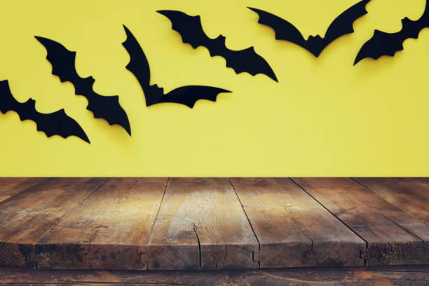 istock Halloween holiday concept. Empty rustic table in front of black bats background. Ready for product display montage. 1054956540