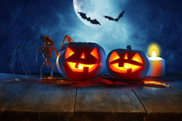 istock Halloween holiday concept. Empty rustic table in front of Pumpkins over wooden table at night scary, haunted and misty forest. Ready for product display montage. 1054956570