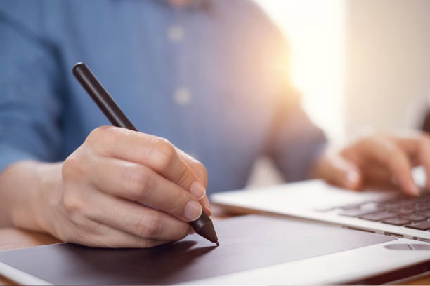 istock Graphic designer using a stylus pen tablets, Photographer drawing and retouching image in laptop computer on desk 1054958782