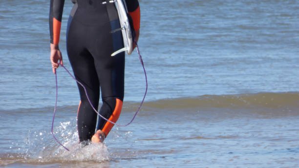 istock Surfer Legs Walking on Becah Holding Surfboard Ocean 1054962124