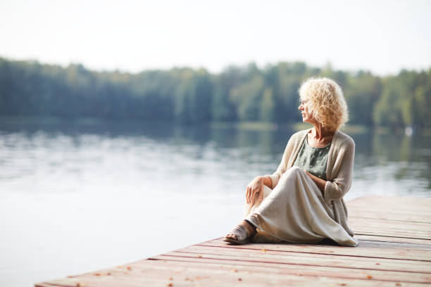 istock Pensive mature lady on pier 1054962744